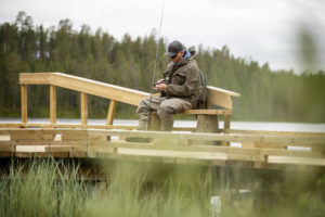 Kalastaja istuu laiturilla