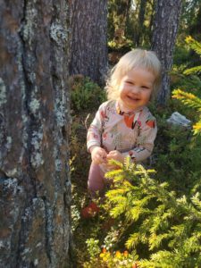 Pikkutyttö hymyilee metsässä