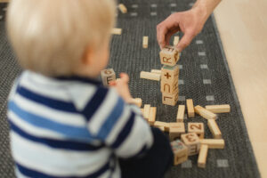 Pieni lapsi ja vanhempi rakentaa puupalikoista tornia