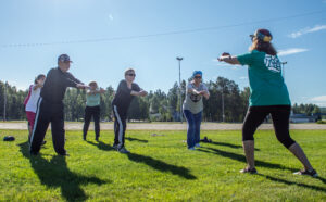 Eläkeläisryhmä harjoittelemassa asahi-liikkeitä nurmikentällä