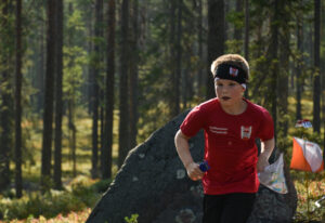 Poika juoksee suunnistaessaan metsässä