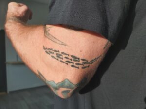 Posion pyrinnön logon muikkuparvi tatuoituna iholle
